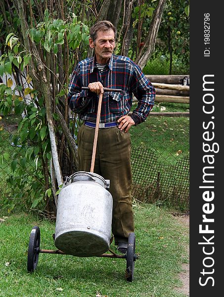 Man in checkered shirt standing and holding a cart with containers for water. Man in checkered shirt standing and holding a cart with containers for water