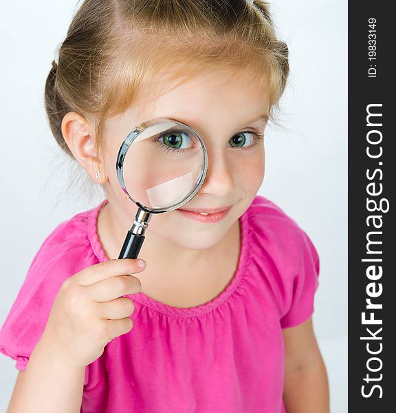 Beautiful little girl looking through a magnifying glass