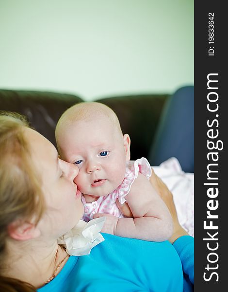 Young woman lying on her back on a couch kissing her little baby. Young woman lying on her back on a couch kissing her little baby