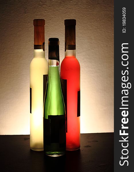 Many bottles of green white and red wine , on a golden background. Many bottles of green white and red wine , on a golden background.