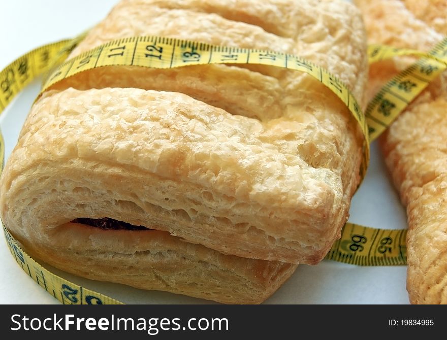 Flaky buns with red jam rolled with yellow measure, focus on the left upper corner. Flaky buns with red jam rolled with yellow measure, focus on the left upper corner