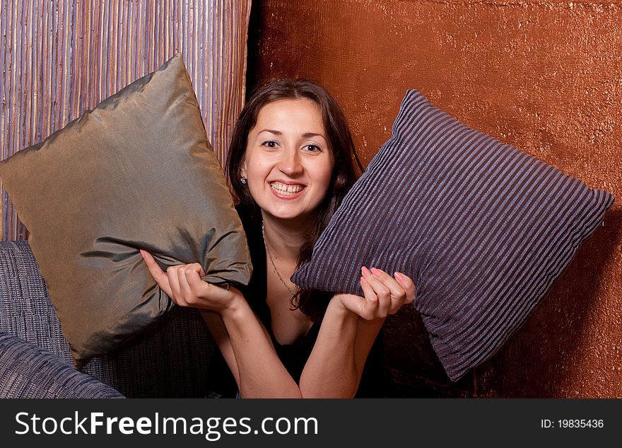 The girl looks out of pillows and coquettish smiles. The girl looks out of pillows and coquettish smiles