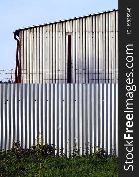 Barbed wire on the metal wall with blue sky background