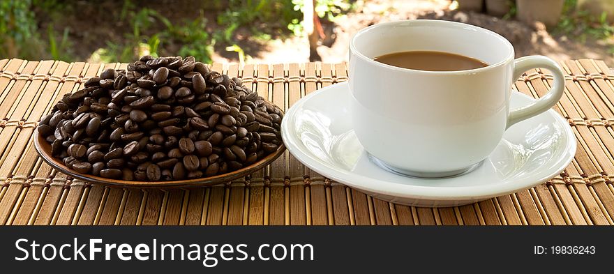 Cup of coffee and coffee seed on plate. Cup of coffee and coffee seed on plate