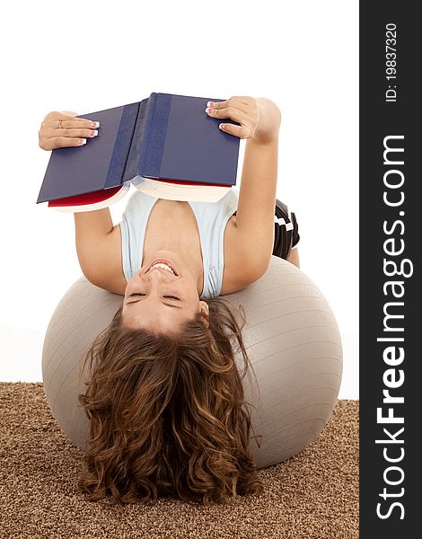 A female laying on her exercise ball taking a break to read a good book. A female laying on her exercise ball taking a break to read a good book.
