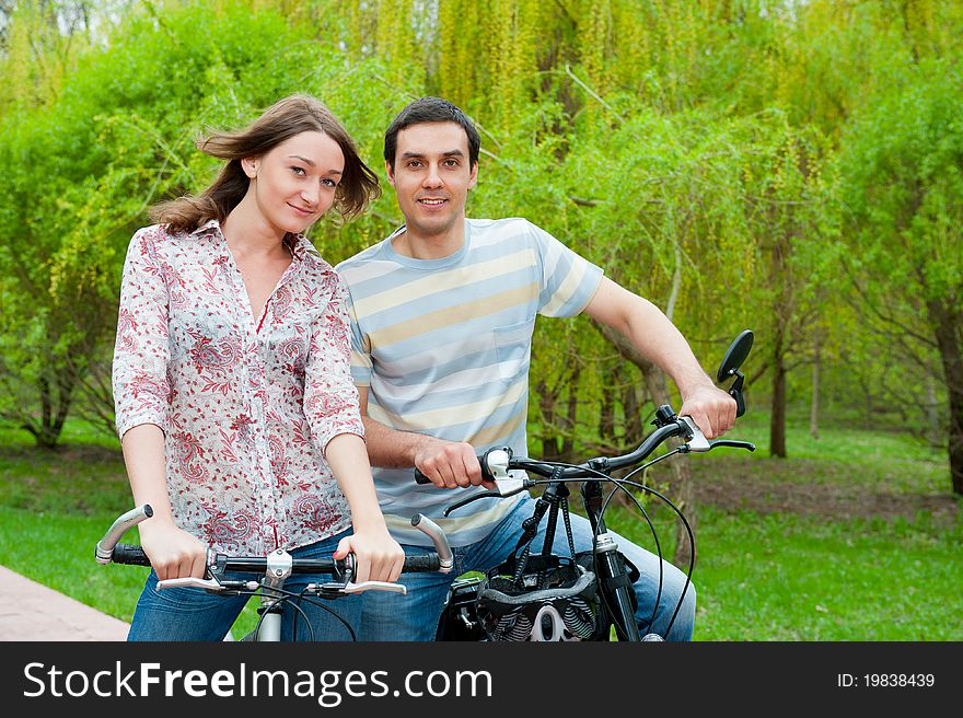 Happy young couple riding bicycles in a park