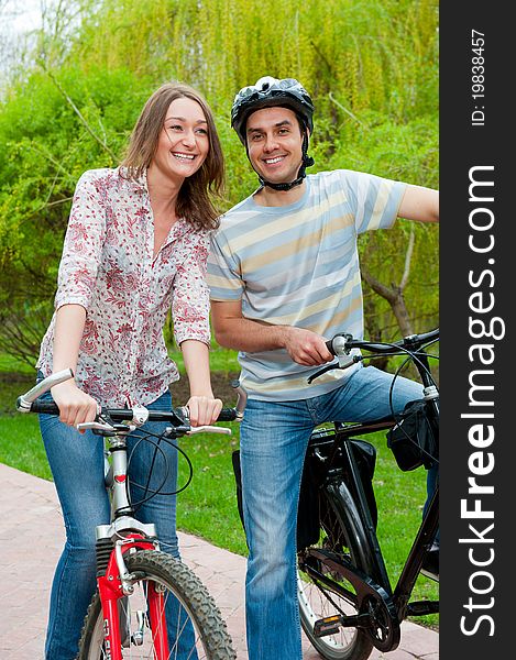 Happy young couple riding bicycles in a park