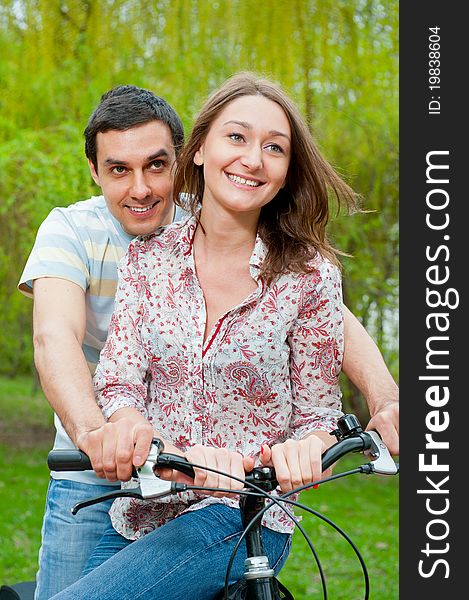 Happy young couple riding bicycle in a park. Happy young couple riding bicycle in a park