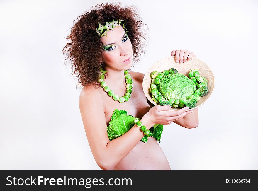 Beautiful pregnant young woman dressed in cabbage isolated on white