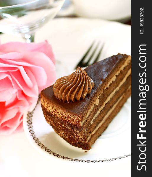 Chocolate cake on white plate and rose