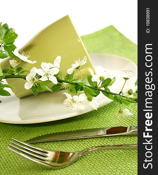 Plate, fork, knife and spring branch on green napkin