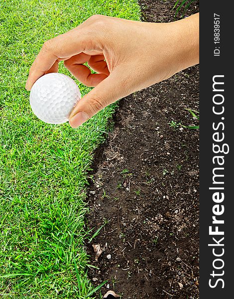 Hand holding golf ball on green grass s shape