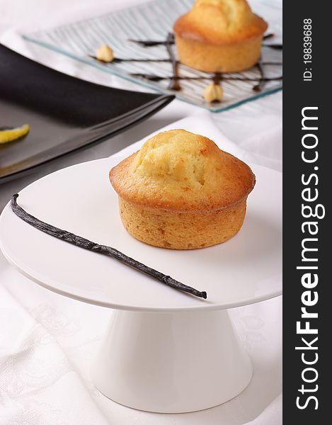 Vanilla muffin on a cake stand and assorted muffins out of focus in the background. Selective focus, shallow DOF