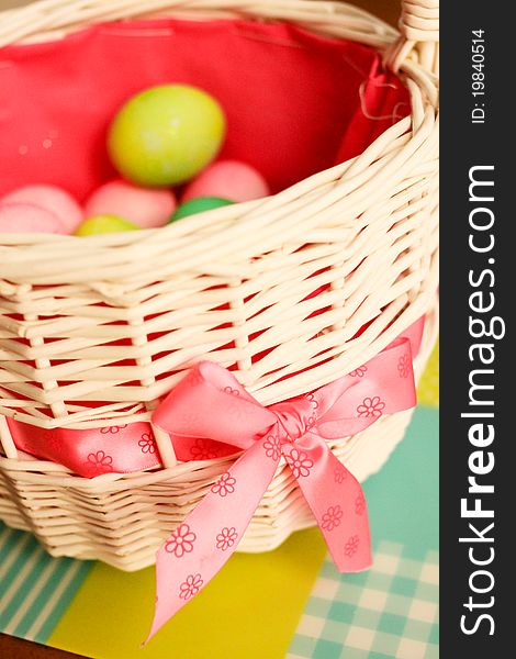 Colorful dyed eggs rest inside a white basket with bright pink bow. Colorful dyed eggs rest inside a white basket with bright pink bow.