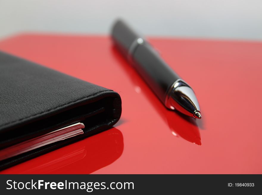 Business notepad and pen on a red background. Business notepad and pen on a red background