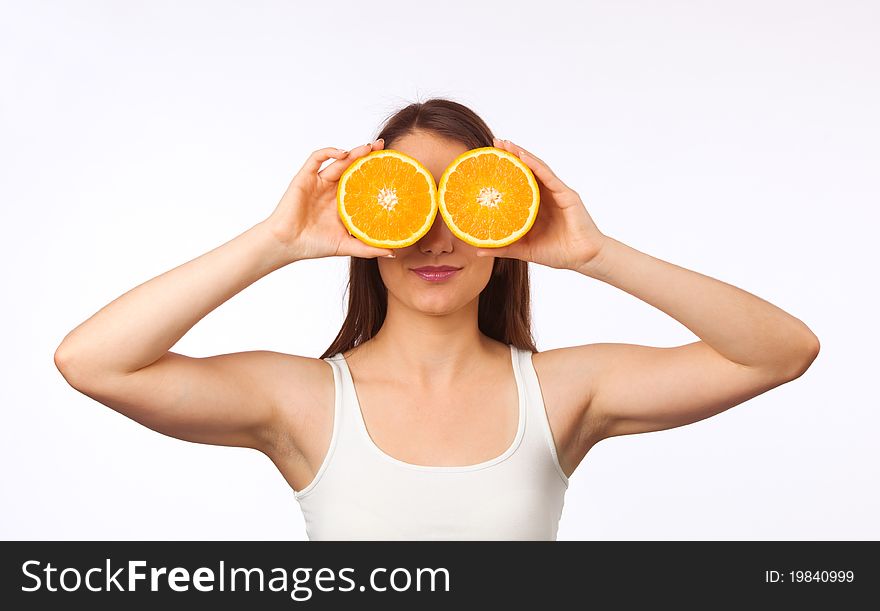 Young woman holding two halves of orange in front of her eyes. Young woman holding two halves of orange in front of her eyes