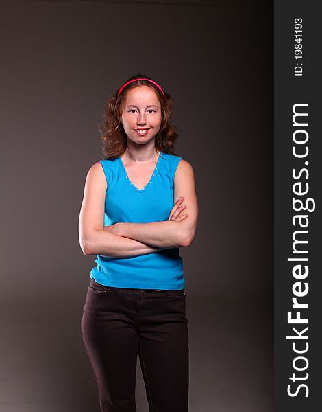 Athletic woman in sporty blue t-shirt is posing on a dark background. Athletic woman in sporty blue t-shirt is posing on a dark background.