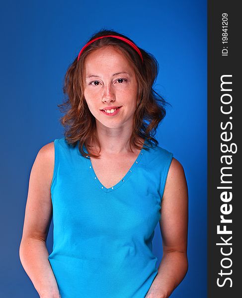 Beautiful athletic woman in sporty blue t-shirt is posing on a dark blue background. Beautiful athletic woman in sporty blue t-shirt is posing on a dark blue background.