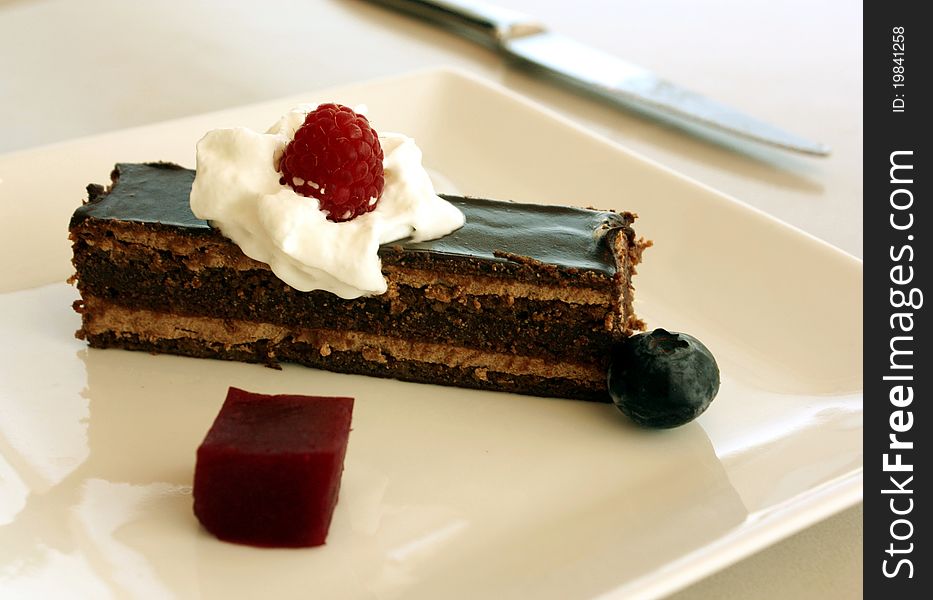 A slice of chocolate cake plated with whipped cream and berries.