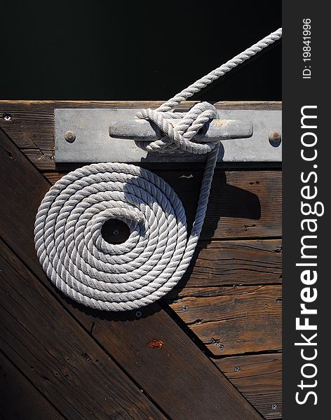 A perfect spiral of white rope is wound around a dock hold. A perfect spiral of white rope is wound around a dock hold.