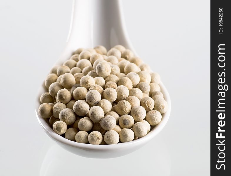 White peppercorns on a porcelain spoon