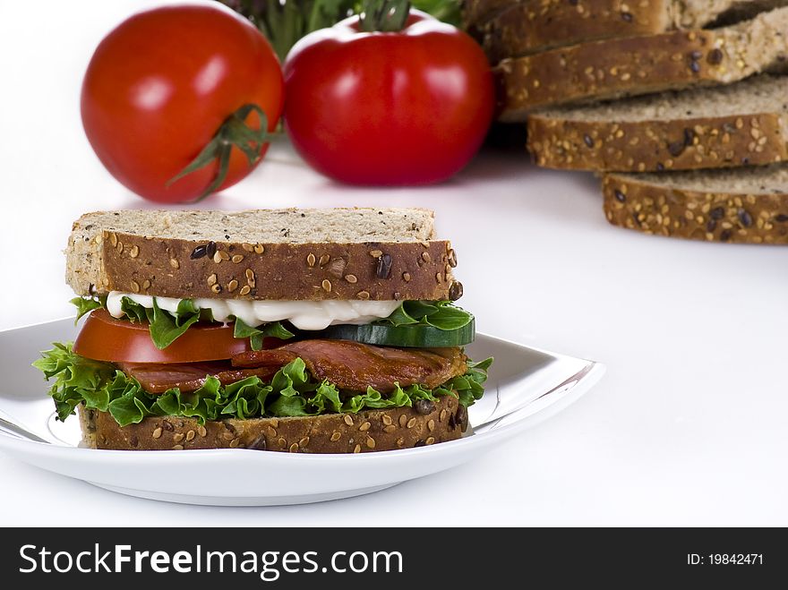 Freshly made bacon sandwich with sliced bread and tomatoes on the background. Freshly made bacon sandwich with sliced bread and tomatoes on the background