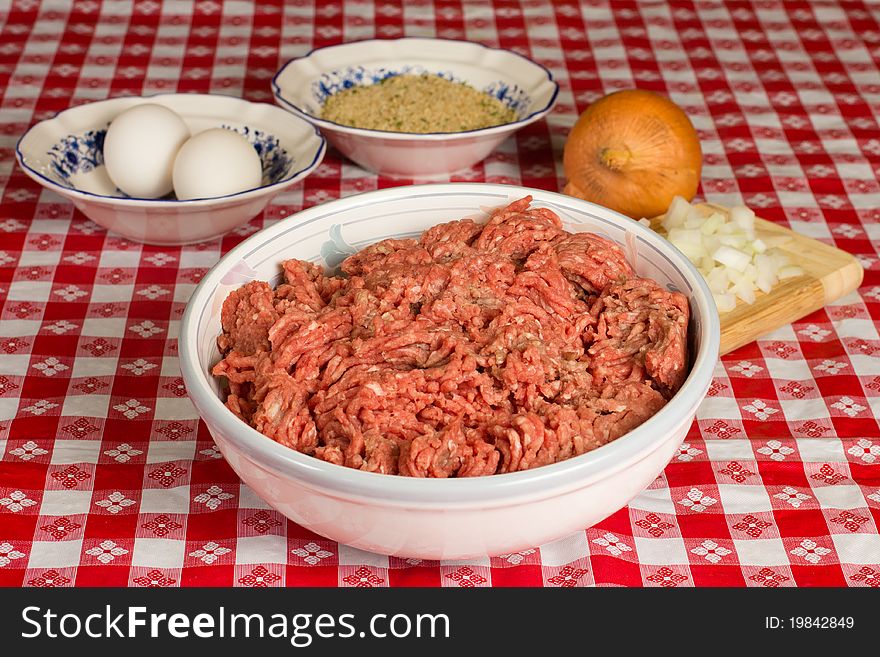 A bowl of uncooked ground beef and the ingredients in preparation of a meatloaf. A bowl of uncooked ground beef and the ingredients in preparation of a meatloaf