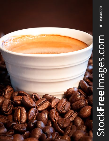 A close-up image of coffee beans with a cup of expresso