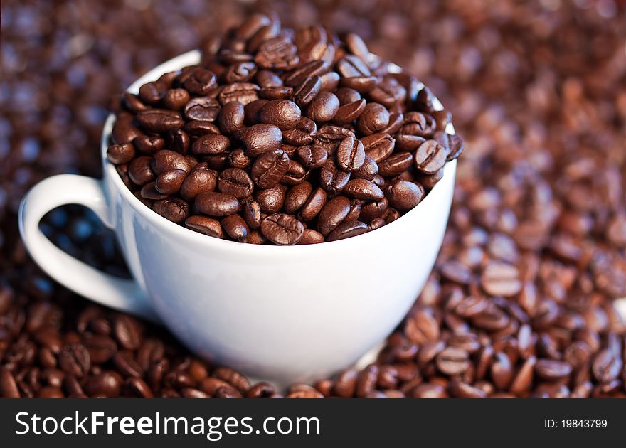 A close-up image of coffee beans in a coffee cup and its surroundings.