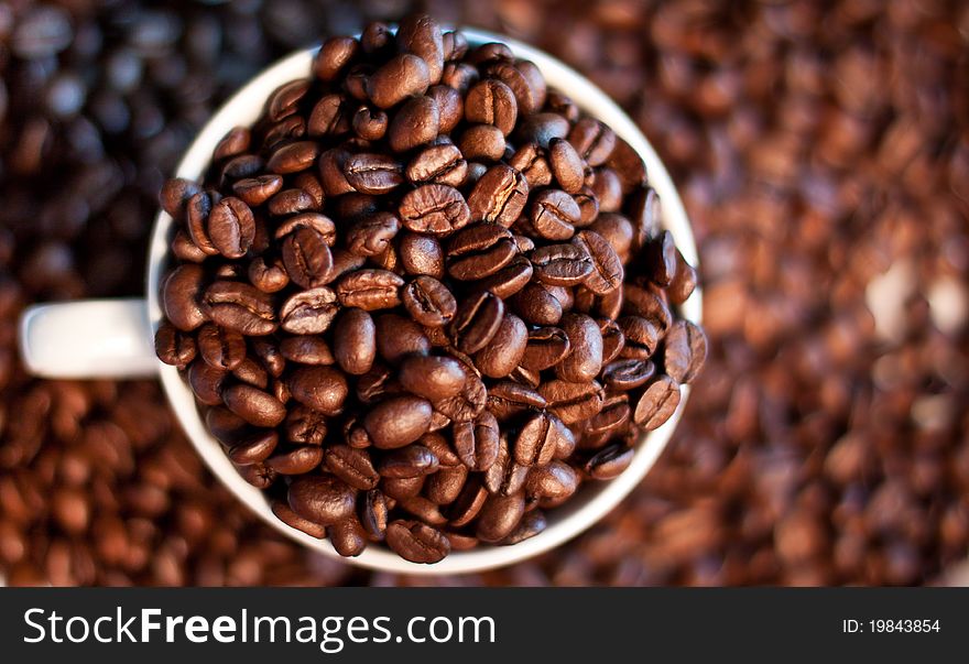 A close-up image of coffee beans in a coffee cup and its surroundings.