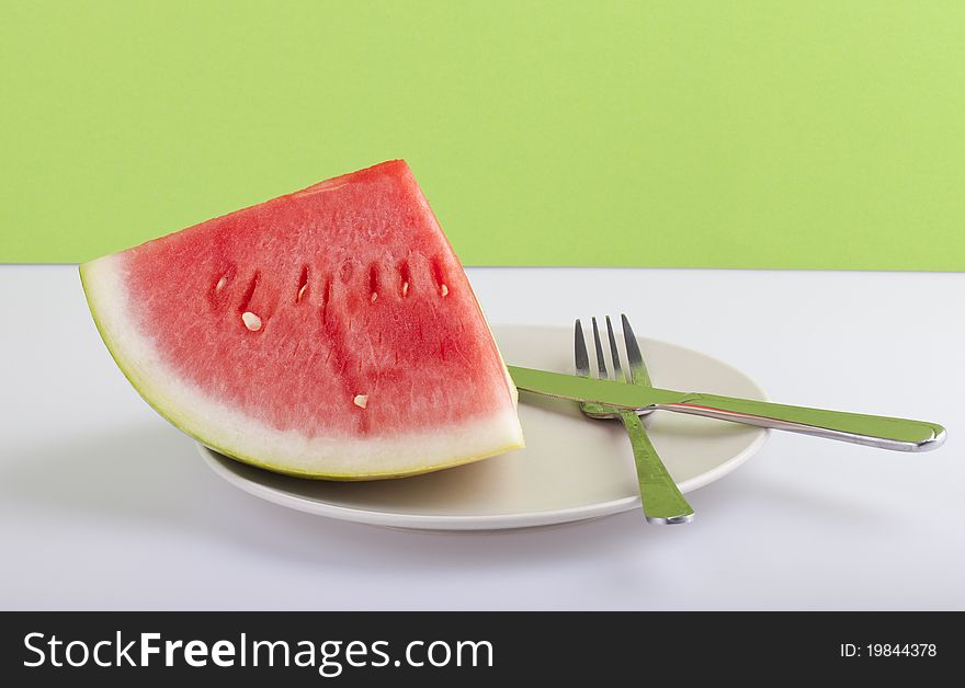 Studio-shot of a plate with fresh piece of watermelon, on a green background