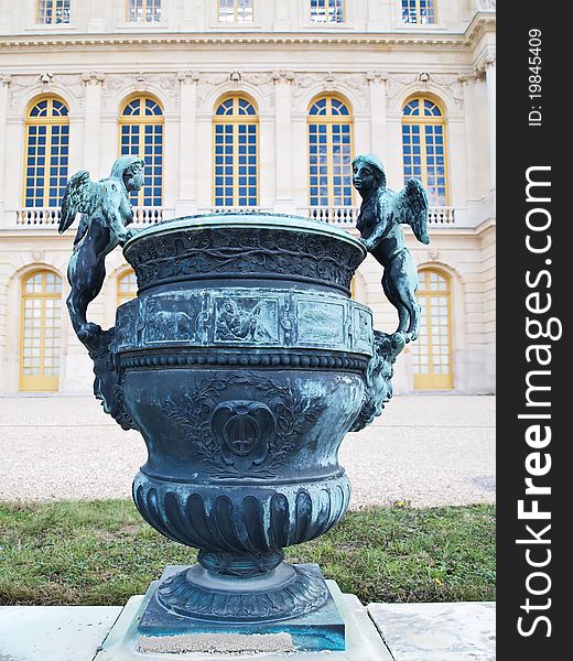 A beautiful vase with bronze angel at foreground of Castle of Versaille in France , Europe. A beautiful vase with bronze angel at foreground of Castle of Versaille in France , Europe