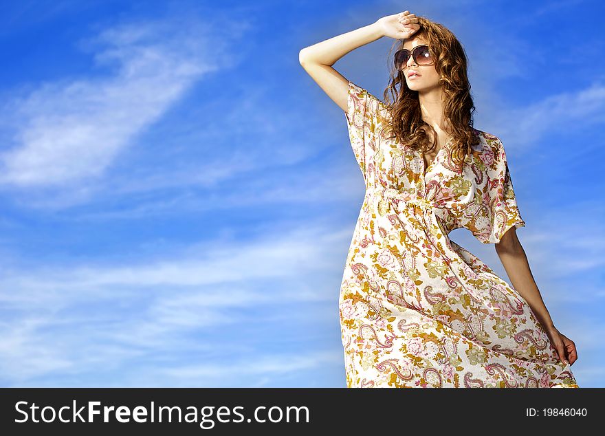 Portrait of beautiful brunette girl in sunglasses on background blue sky. Portrait of beautiful brunette girl in sunglasses on background blue sky