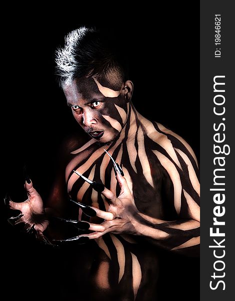 Asian male with black stripe body paint and long claws on black background. Asian male with black stripe body paint and long claws on black background