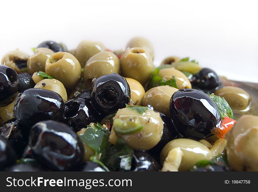 A close up shot of black and green olives marinated in herbs, on a white background. Copy space if needed.