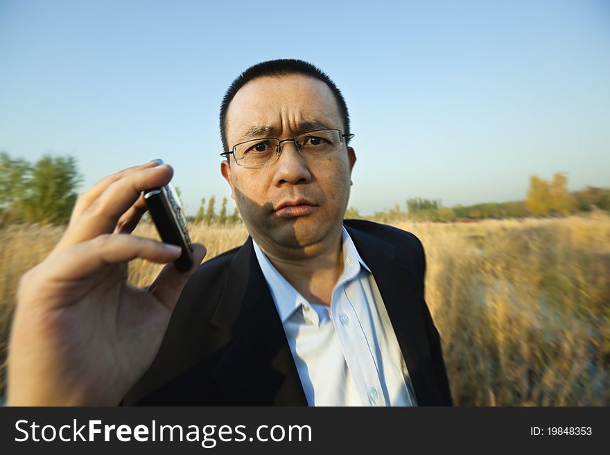 Asian businessman holding a cellphone; motion blur