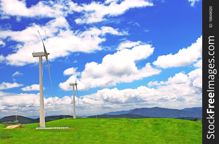 Windmills on a green plain under blue sky. Windmills on a green plain under blue sky