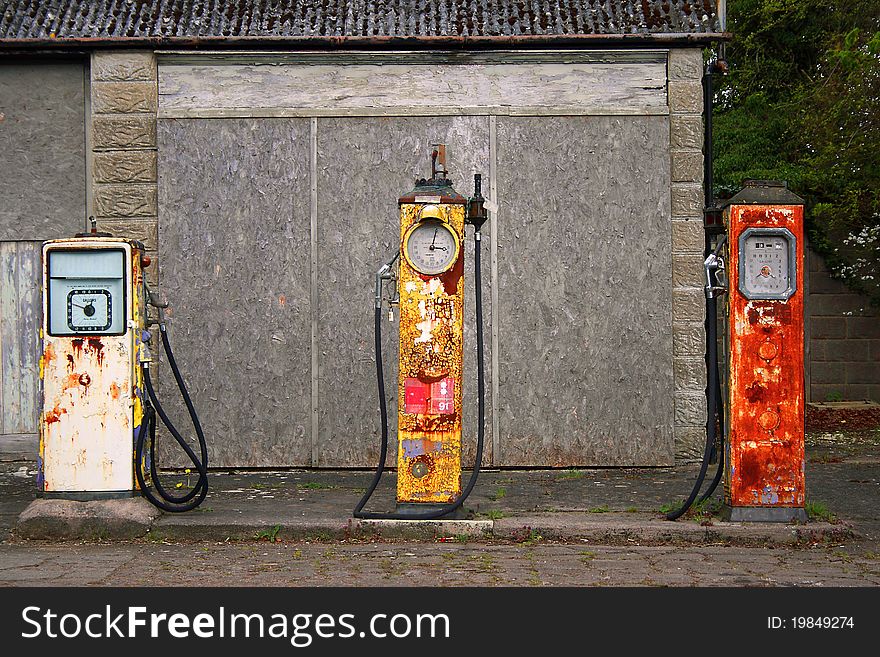 An old and decaying derelict English village filling station/Garage.There are three filling pumps and each one is unique in shape size and colour. An old and decaying derelict English village filling station/Garage.There are three filling pumps and each one is unique in shape size and colour.