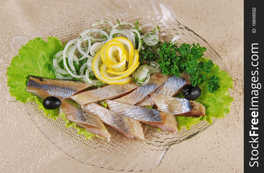 Herring fillet with onion and lemon on glass plate. Herring fillet with onion and lemon on glass plate