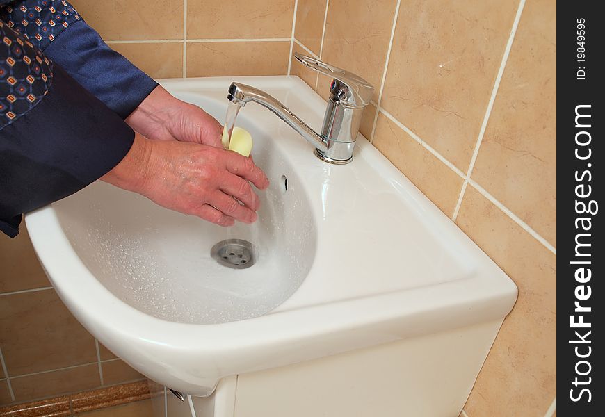 A person washing their hands in the bathroom sink . A person washing their hands in the bathroom sink .