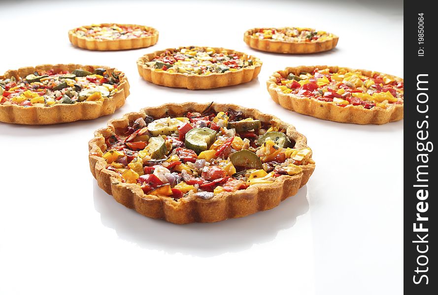 Cheese and tomato quiche arranged in rows on isolated white background