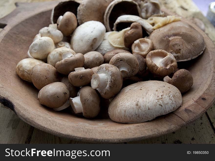Mushrooms varieties arranged on an old wooden bowl
