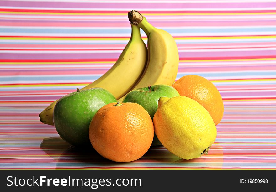 A bright group of fruit together on a shiny multi coloured surface with the concept of healthy eating. A bright group of fruit together on a shiny multi coloured surface with the concept of healthy eating.