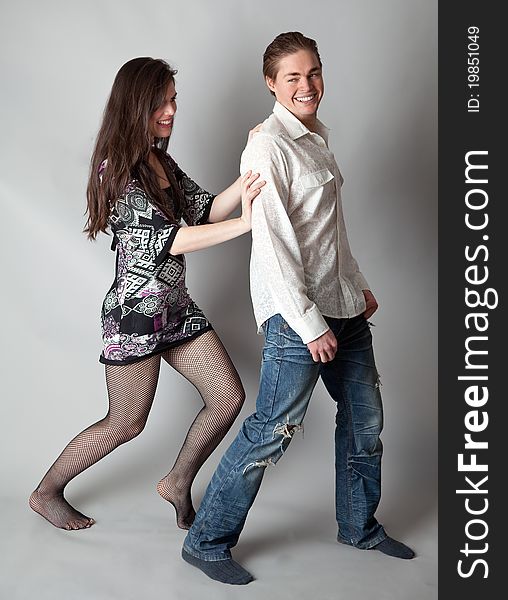 A cute, fun image of a pretty young woman in a dress smiling as she gently pushes an attractive young man. A cute, fun image of a pretty young woman in a dress smiling as she gently pushes an attractive young man.