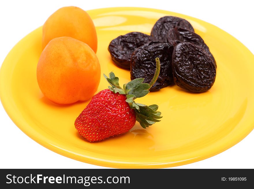 Strawberries, apricots and prunes on the yellow plate. Strawberries, apricots and prunes on the yellow plate