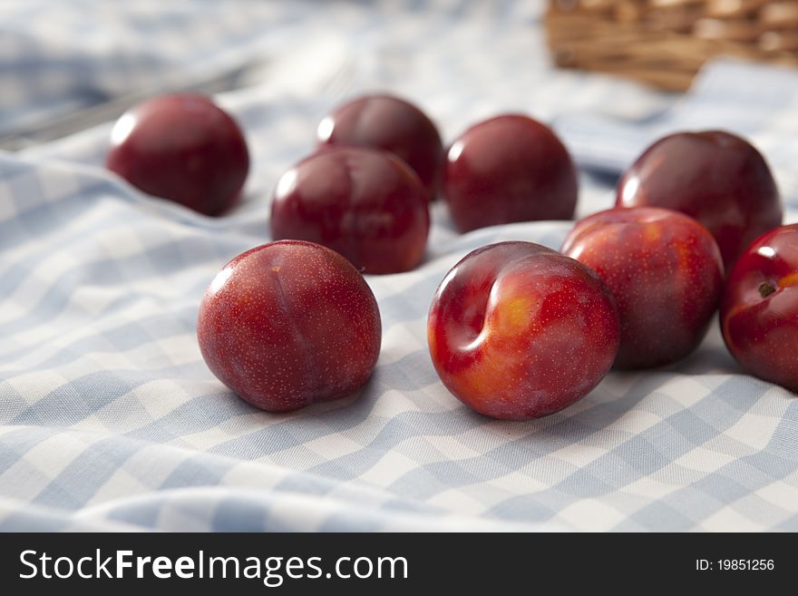 Loose plums scattered on a picnic rug