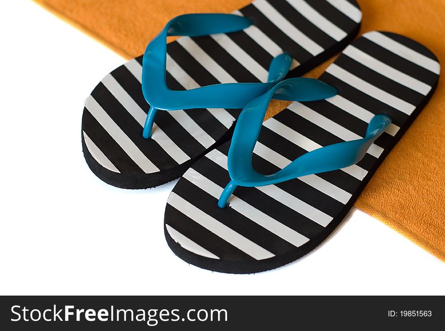 Striped azure and black flip-flops on an orange towel