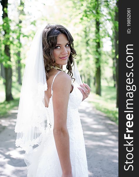 Young bride standing in an alley in the park