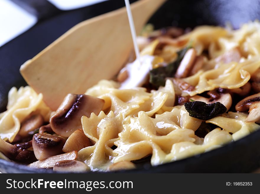 Preparing a dish of farfalle pasta with mushrooms