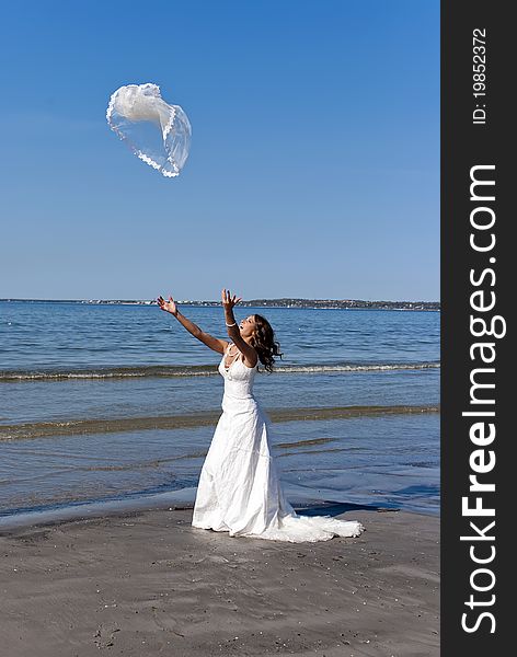 Beautiful young bride throwing the veil near the sea